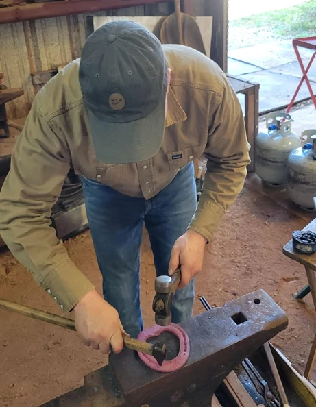 Tylor James at work shaping a horseshoe