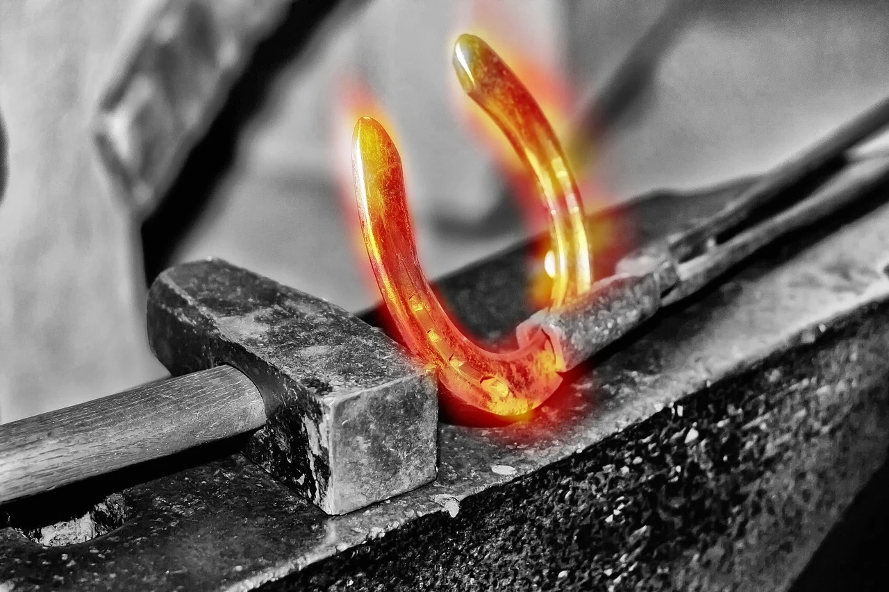 A heated horseshoe being shaped on an anvil